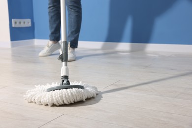 Photo of Woman cleaning floor with string mop indoors, closeup