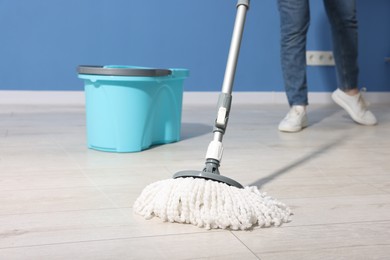 Photo of Woman cleaning floor with string mop indoors, closeup