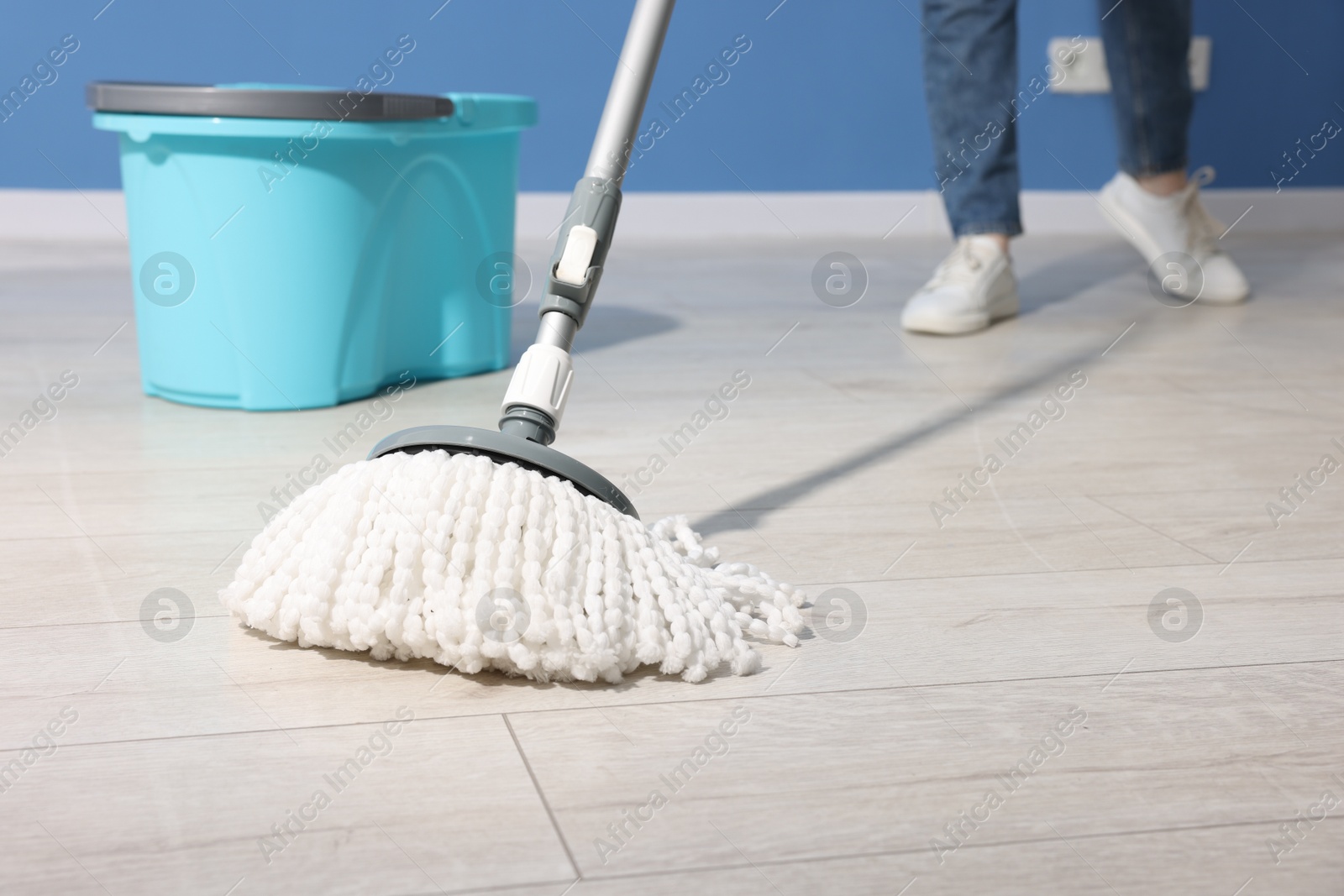 Photo of Woman cleaning floor with string mop indoors, closeup