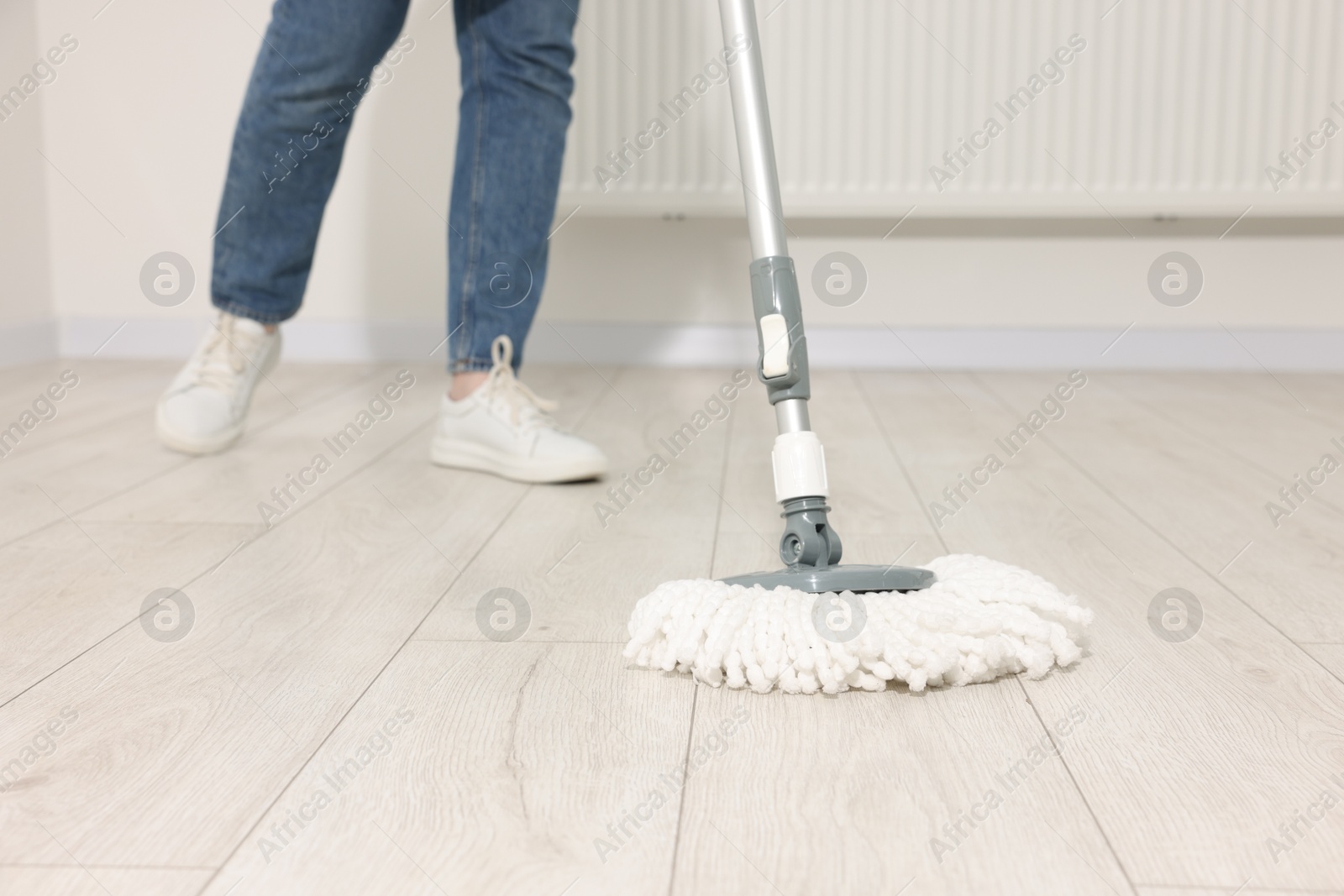 Photo of Woman cleaning floor with string mop indoors, closeup