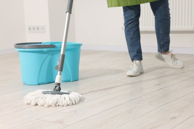 Photo of Woman cleaning floor with string mop indoors, closeup