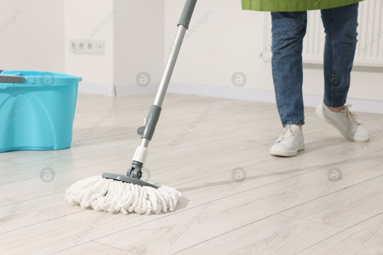 Photo of Woman cleaning floor with string mop indoors, closeup