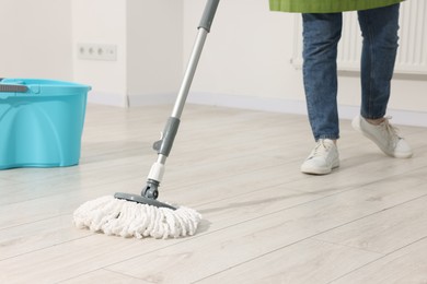 Photo of Woman cleaning floor with string mop indoors, closeup