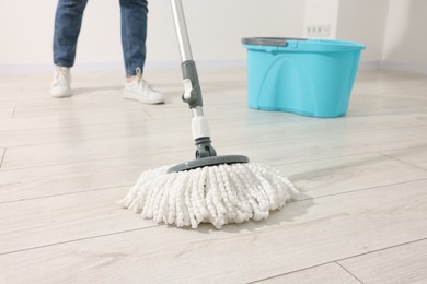 Photo of Woman cleaning floor with string mop indoors, closeup