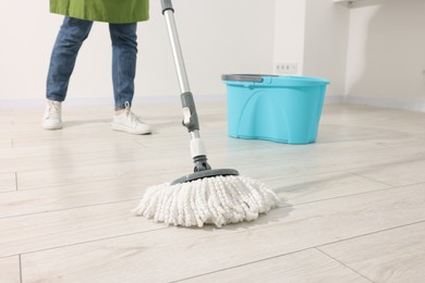 Photo of Woman cleaning floor with string mop indoors, closeup