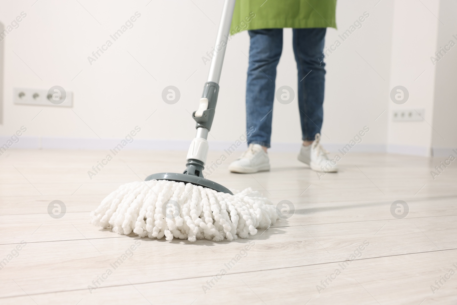 Photo of Woman cleaning floor with string mop indoors, closeup