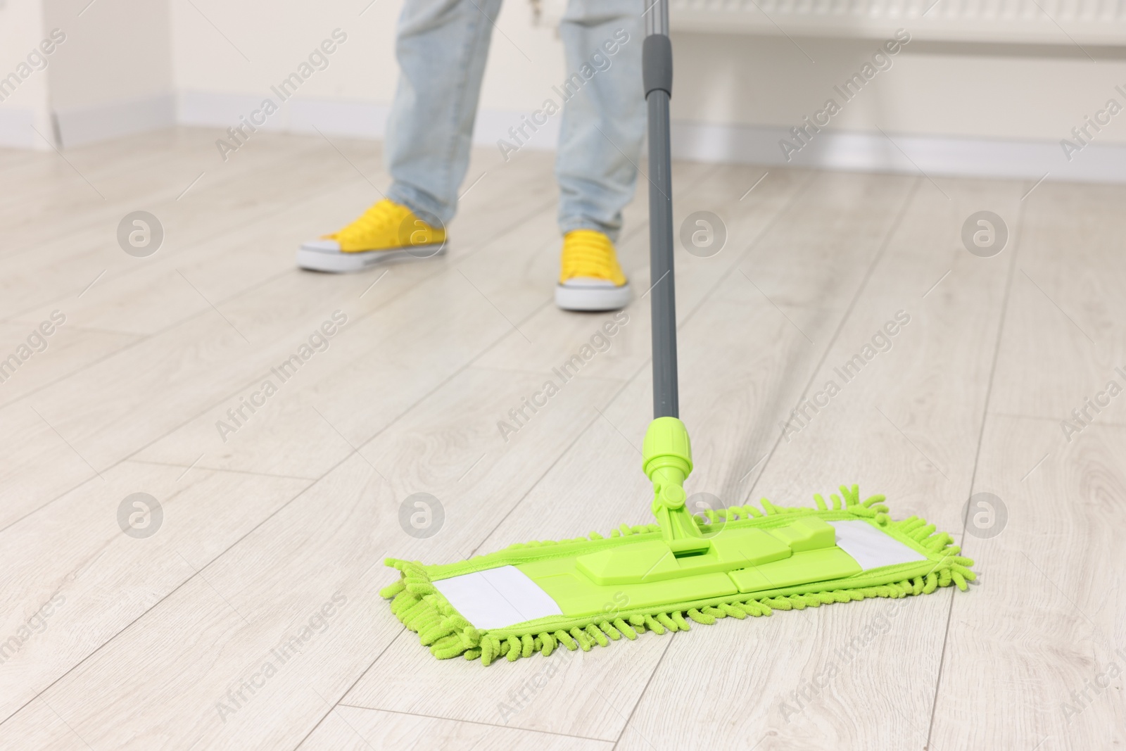 Photo of Woman cleaning floor with microfiber mop indoors, closeup