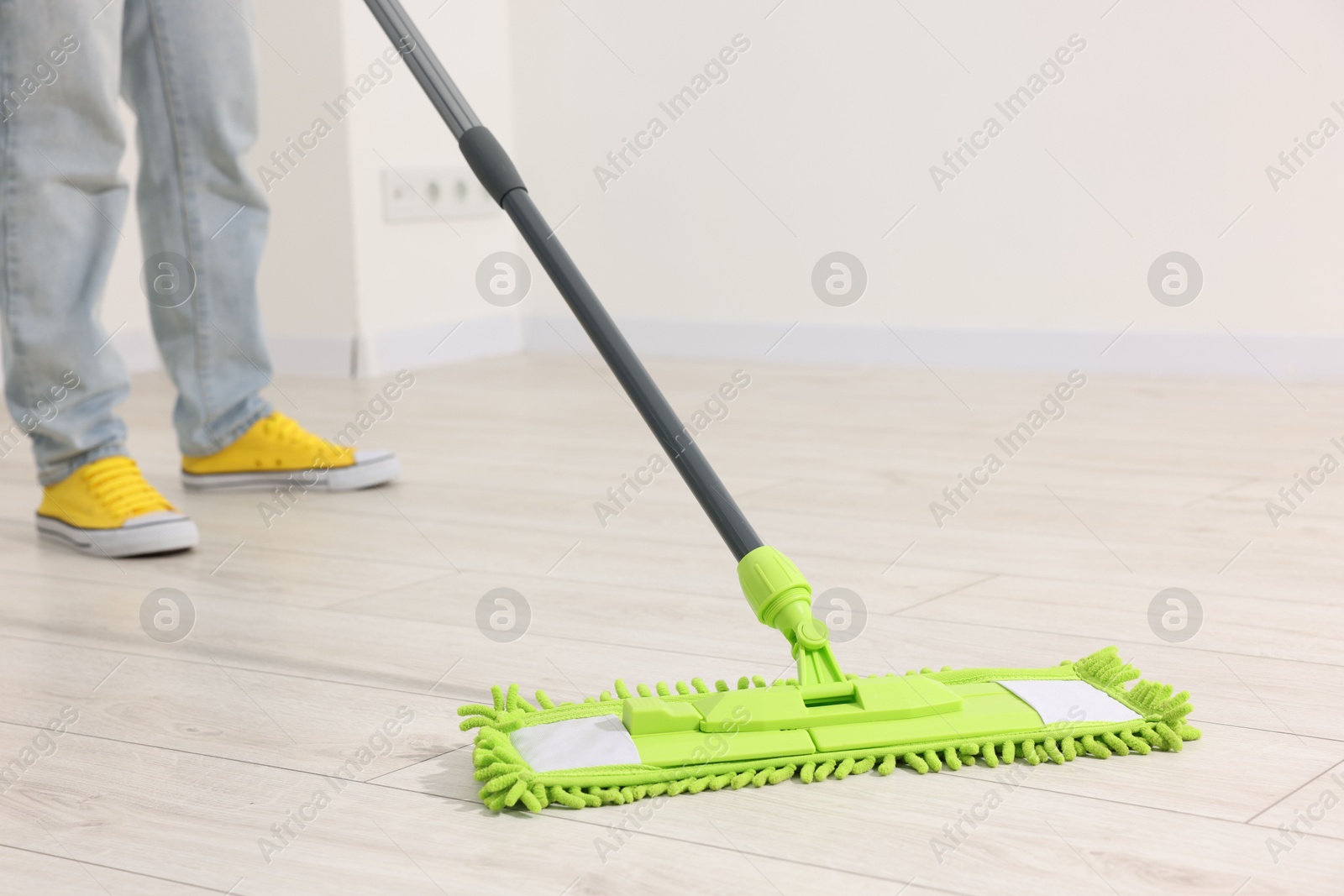 Photo of Woman cleaning floor with microfiber mop indoors, closeup