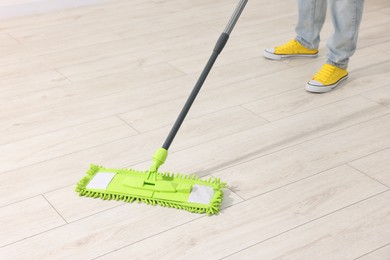 Photo of Woman cleaning floor with microfiber mop indoors, closeup