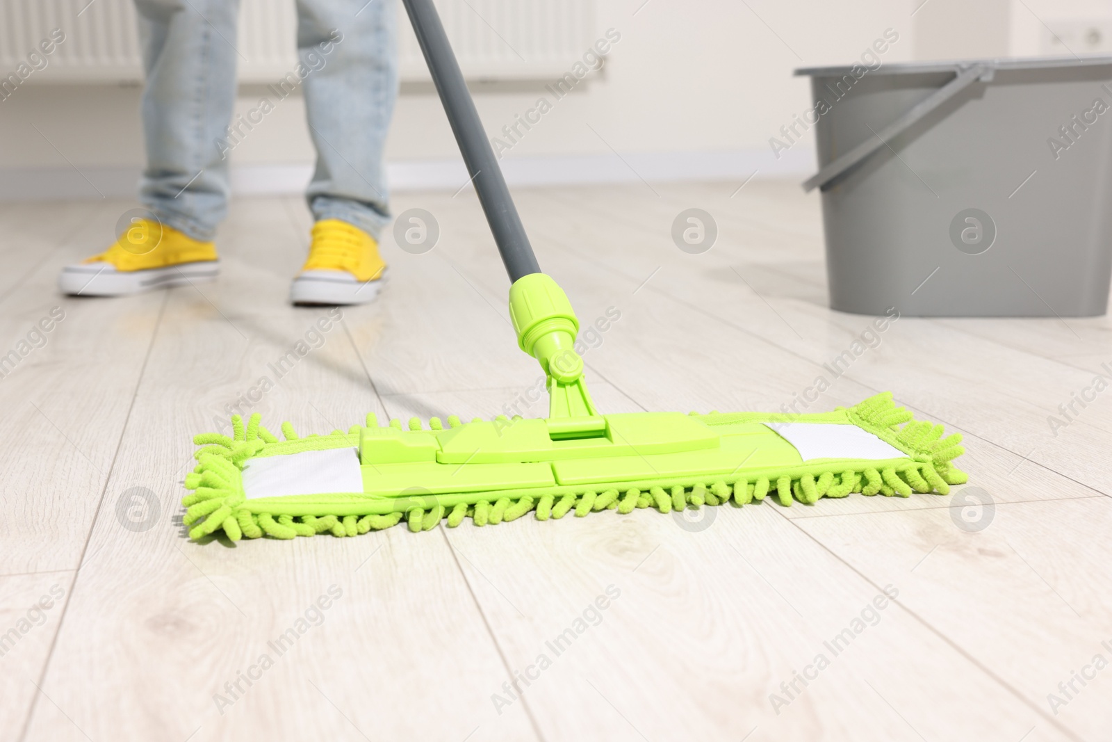 Photo of Woman cleaning floor with microfiber mop indoors, closeup