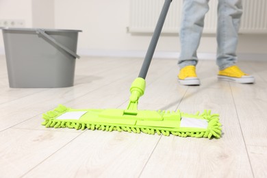 Photo of Woman cleaning floor with microfiber mop indoors, closeup