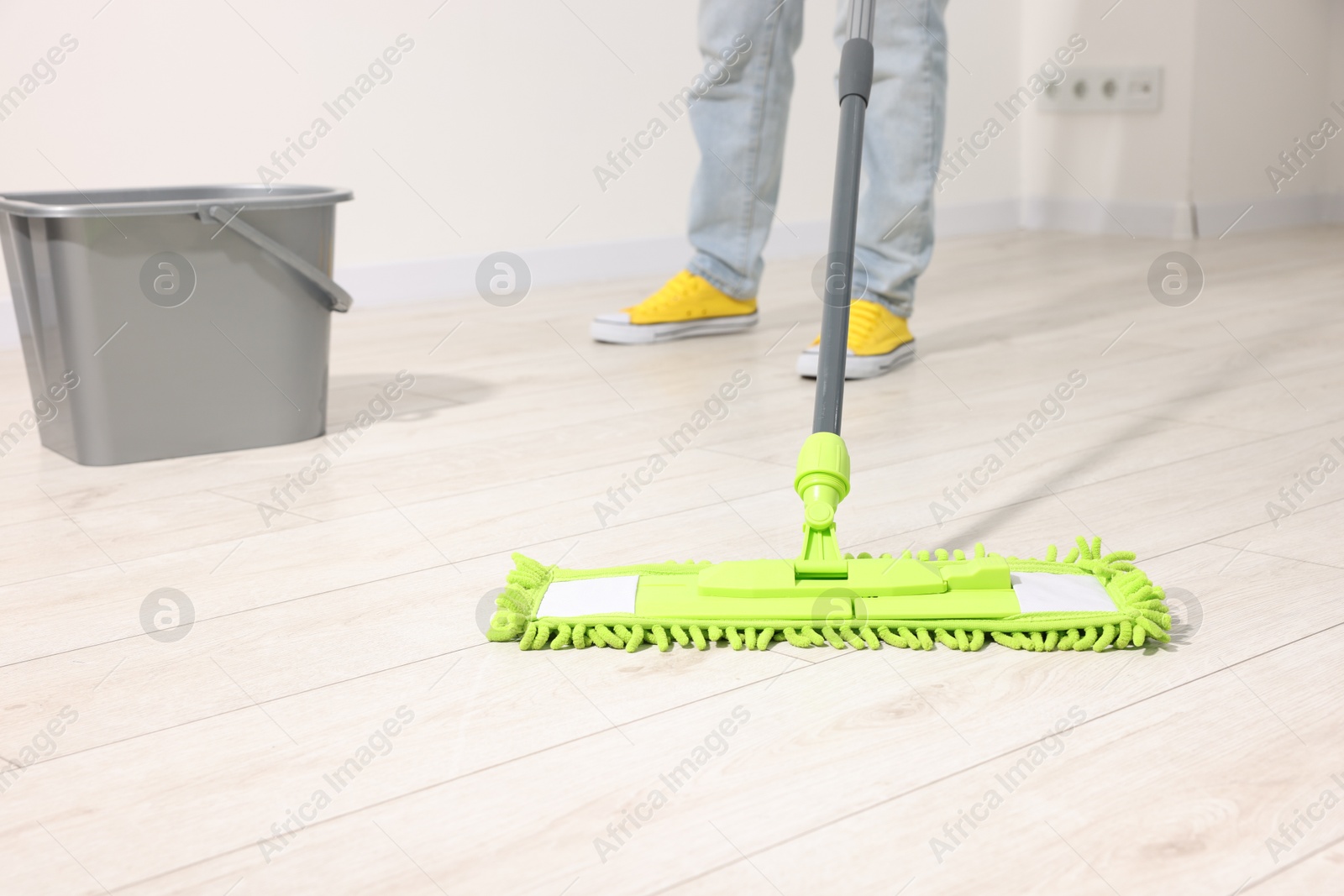 Photo of Woman cleaning floor with microfiber mop indoors, closeup