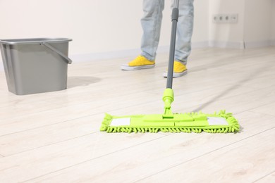 Photo of Woman cleaning floor with microfiber mop indoors, closeup