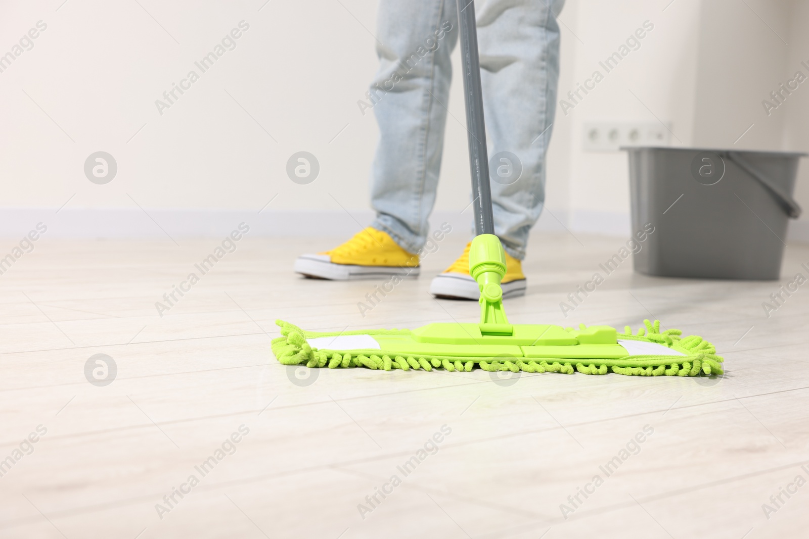 Photo of Woman cleaning floor with microfiber mop indoors, closeup