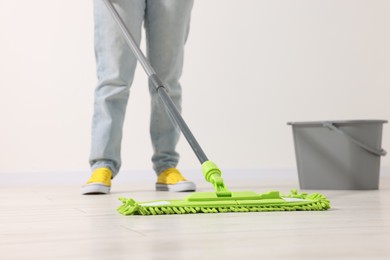 Photo of Woman cleaning floor with microfiber mop indoors, closeup