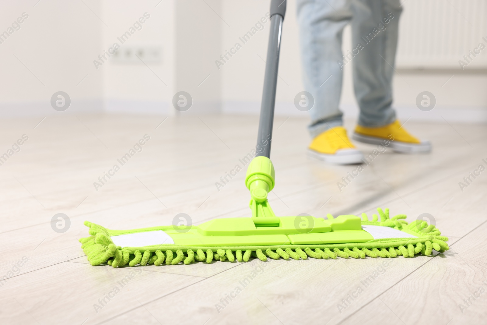 Photo of Woman cleaning floor with microfiber mop indoors, closeup