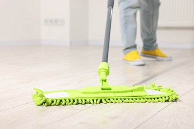 Photo of Woman cleaning floor with microfiber mop indoors, closeup