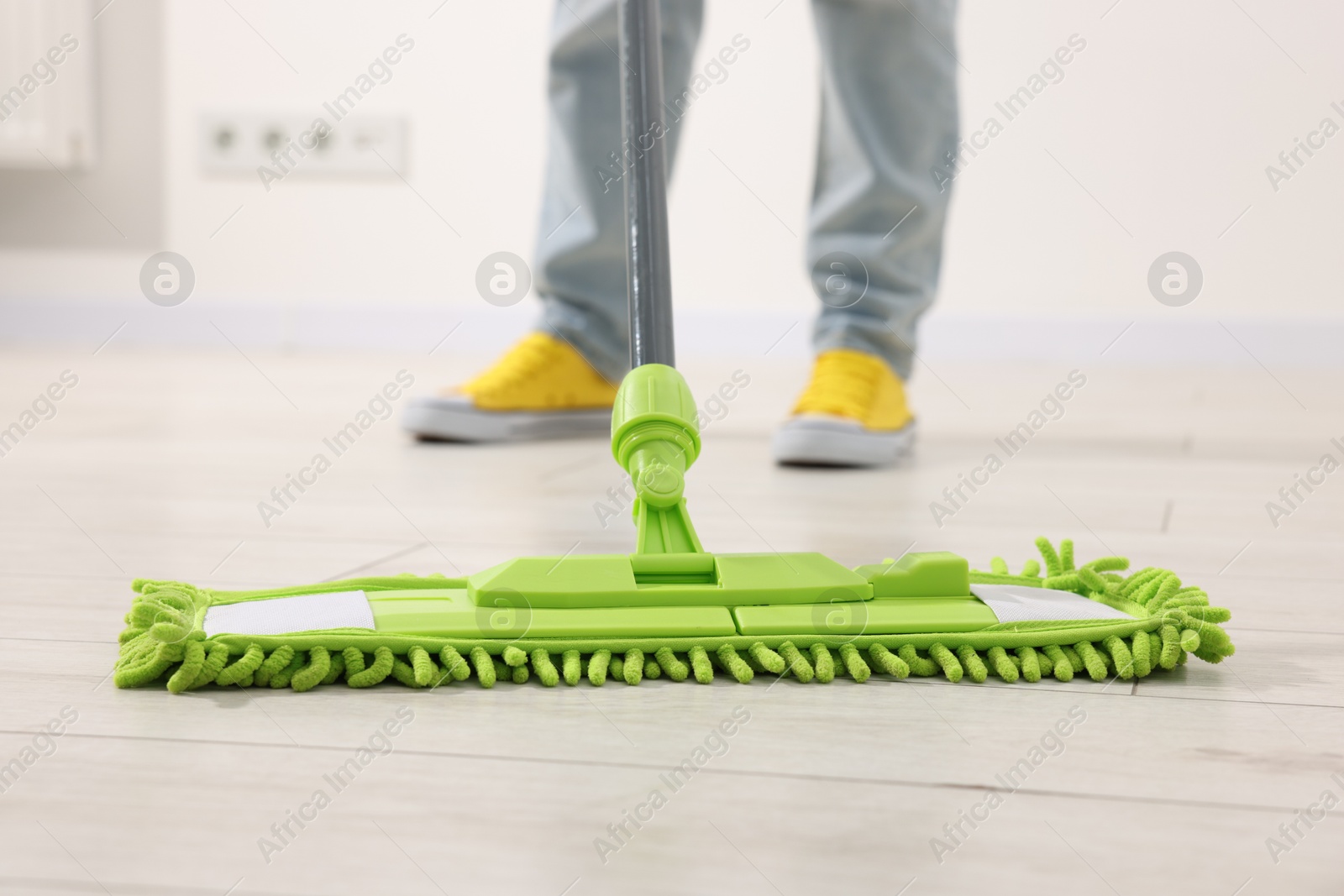 Photo of Woman cleaning floor with microfiber mop indoors, closeup