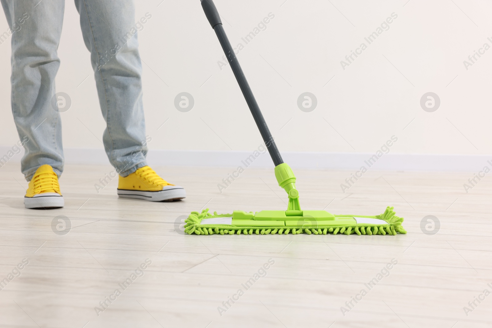 Photo of Woman cleaning floor with microfiber mop indoors, closeup