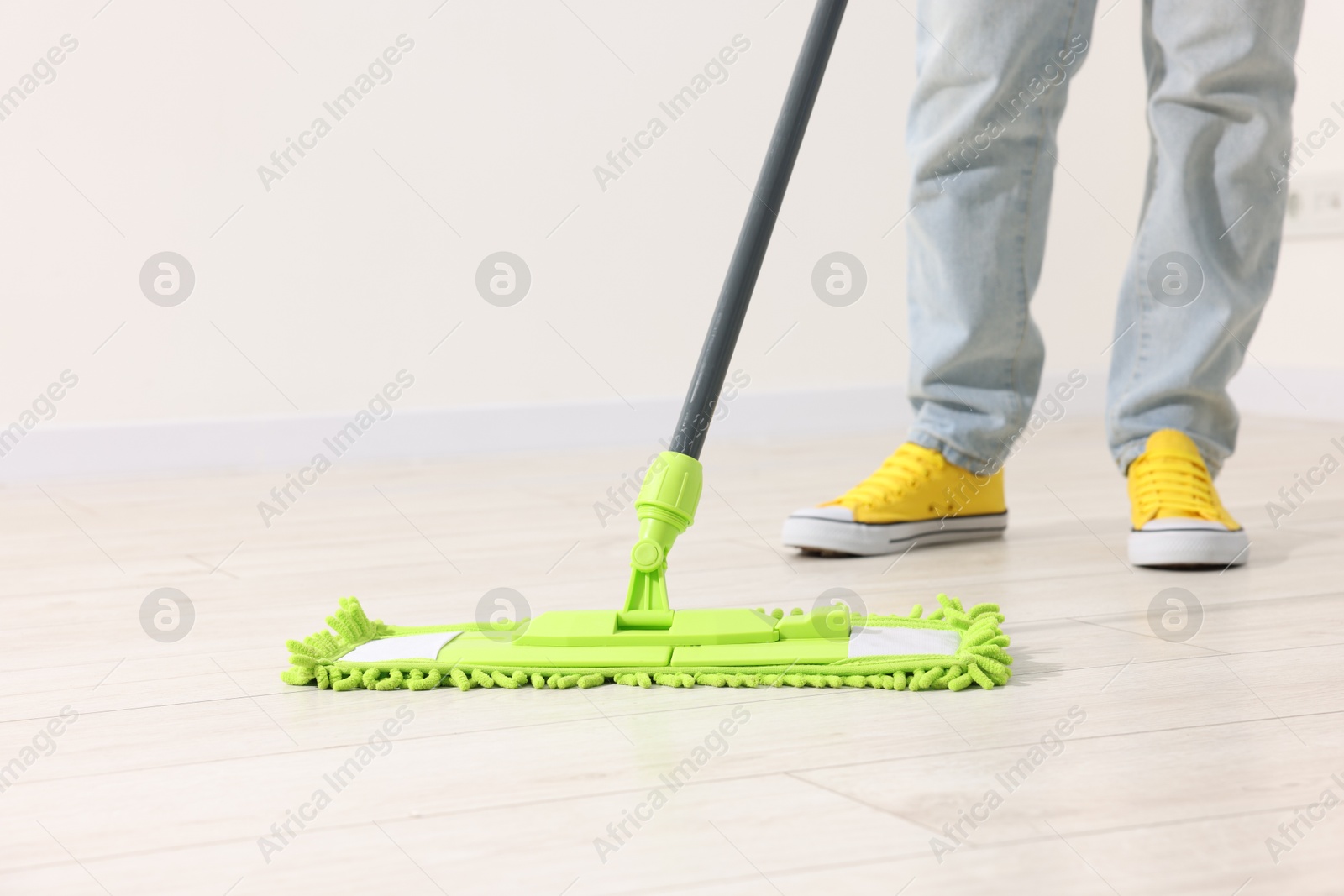 Photo of Woman cleaning floor with microfiber mop indoors, closeup