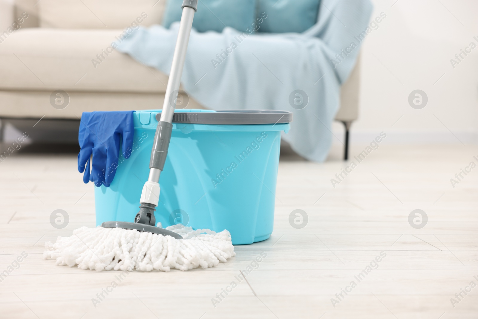 Photo of String mop, bucket and glove on floor indoors, space for text