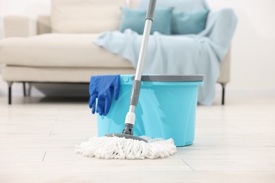 Photo of String mop, bucket and glove on floor indoors