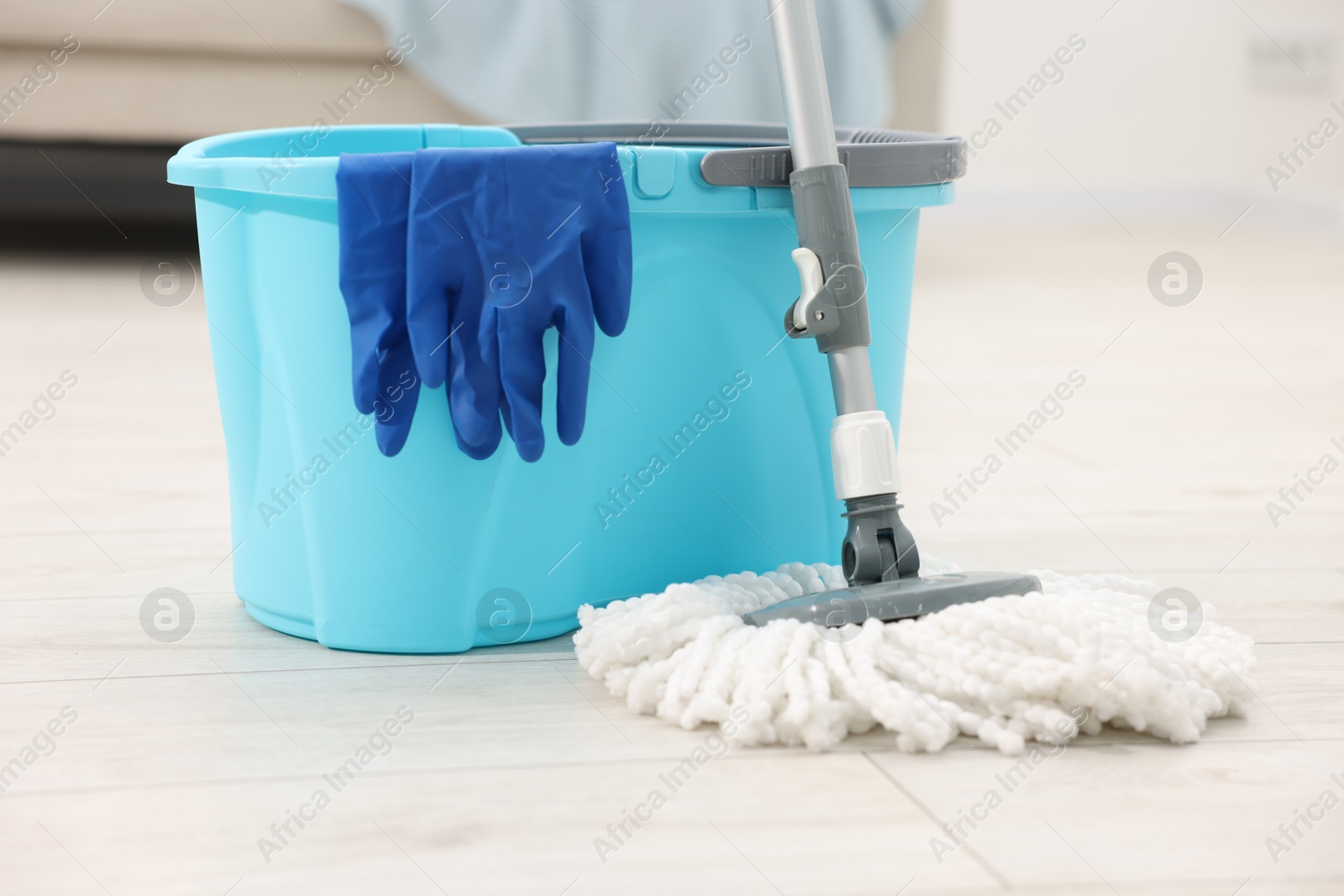 Photo of String mop, bucket and gloves on floor indoors