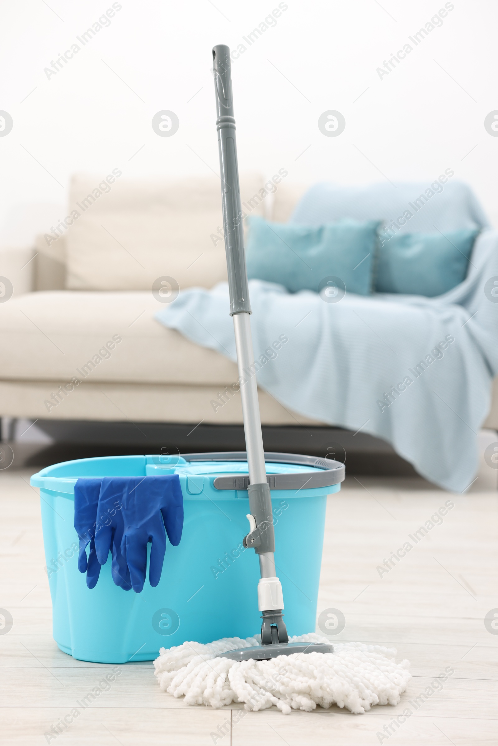 Photo of String mop, bucket and gloves on floor indoors