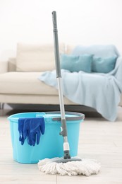 Photo of String mop, bucket and gloves on floor indoors