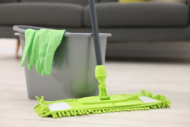 Photo of Microfiber mop, bucket and gloves on floor indoors