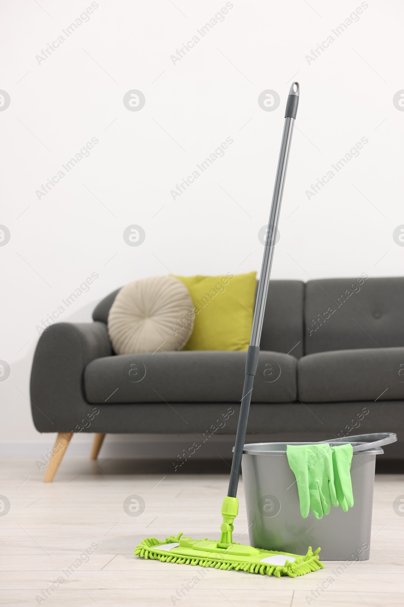 Photo of Microfiber mop, bucket and gloves on floor indoors