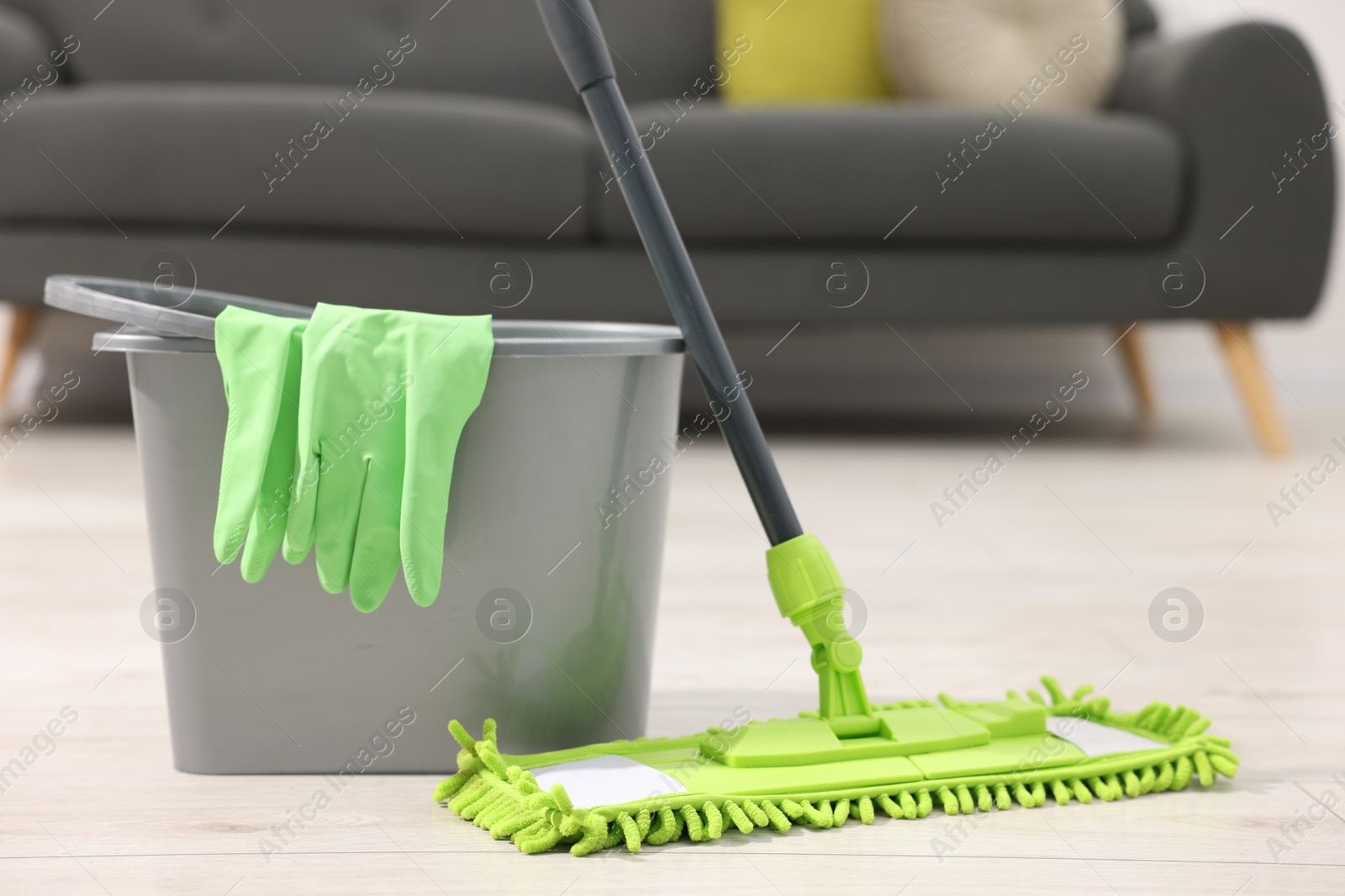 Photo of Microfiber mop, bucket and gloves on floor indoors