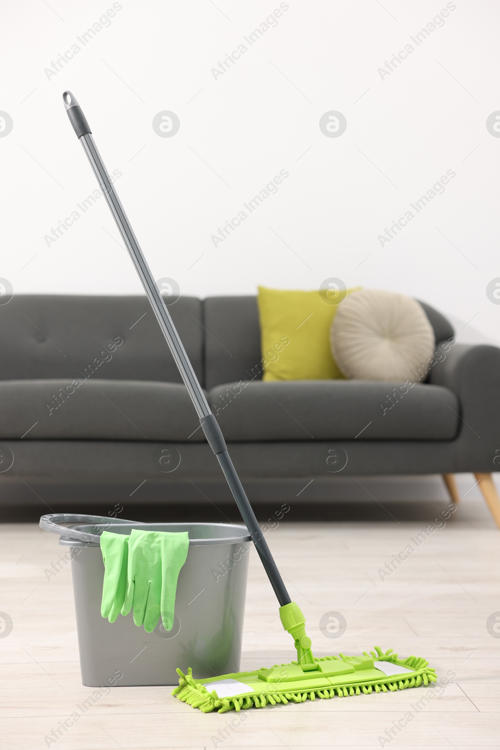 Photo of Microfiber mop, bucket and gloves on floor indoors