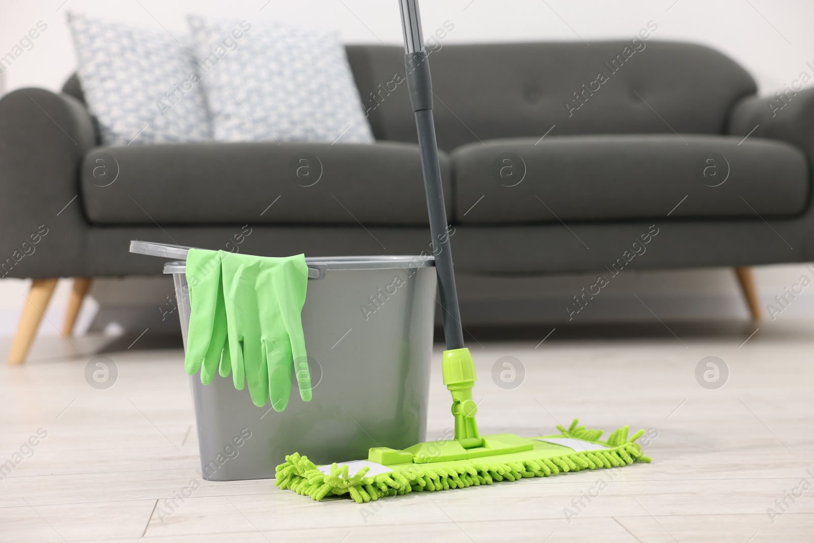 Photo of Microfiber mop, bucket and gloves on floor indoors