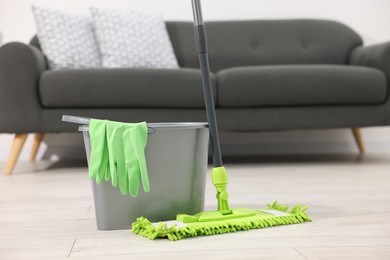 Photo of Microfiber mop, bucket and gloves on floor indoors