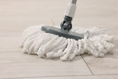 Photo of String mop on wooden floor, closeup. Cleaning equipment