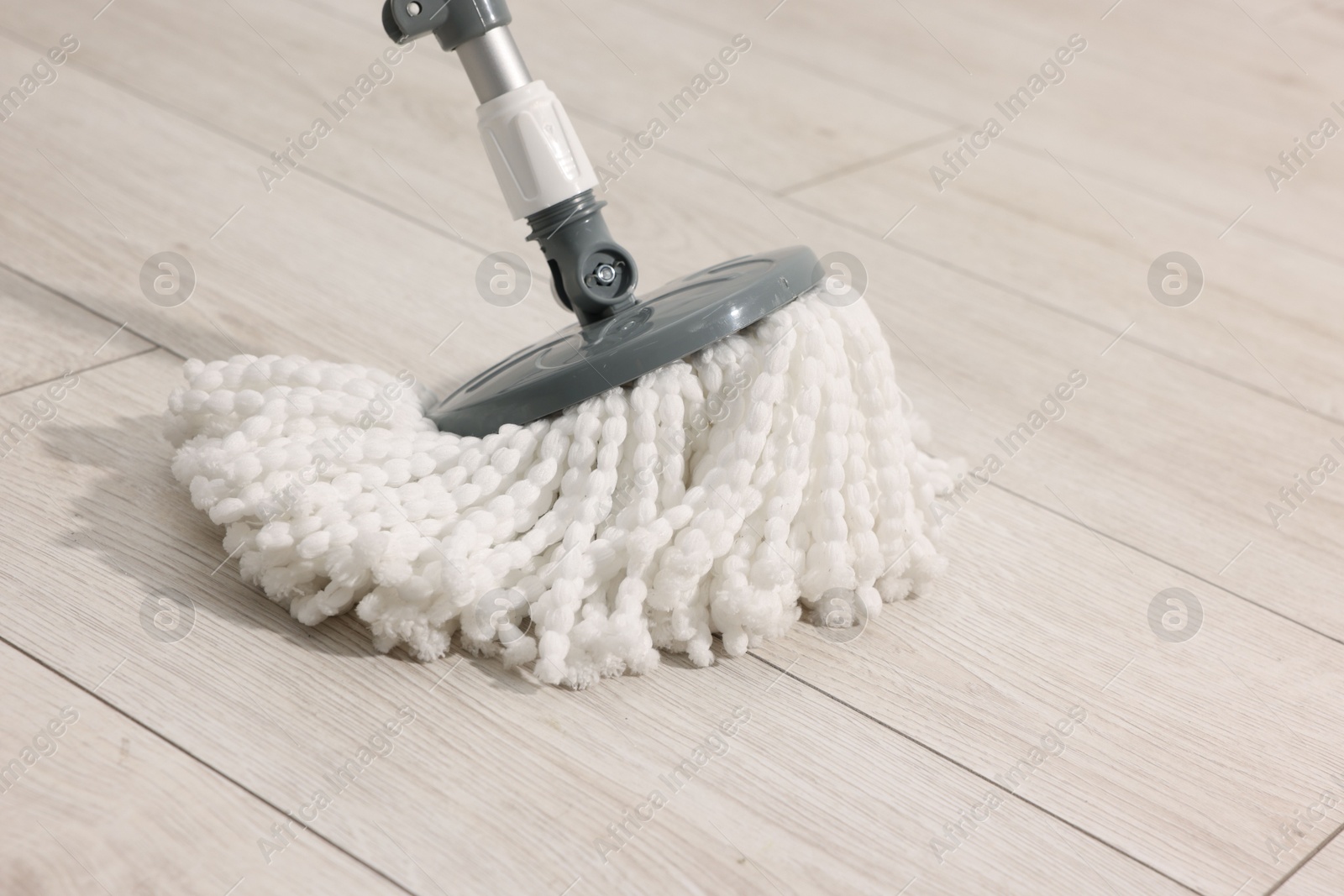 Photo of String mop on wooden floor. Cleaning equipment