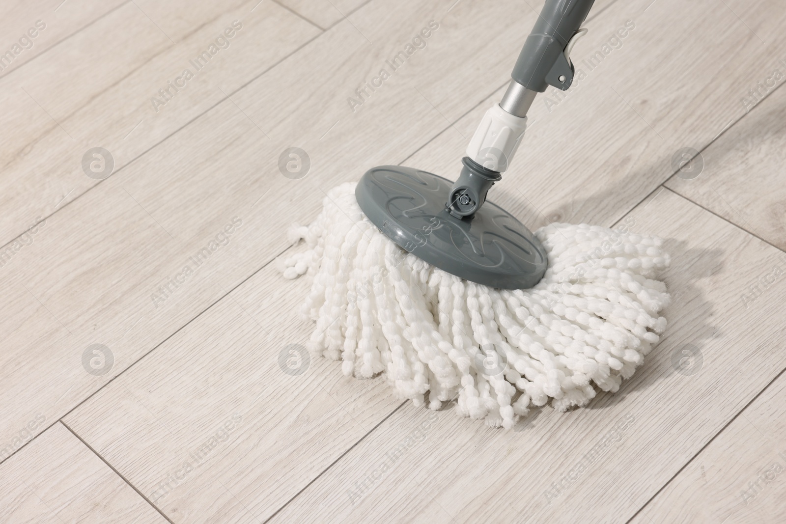 Photo of String mop on wooden floor indoors, space for text. Cleaning equipment