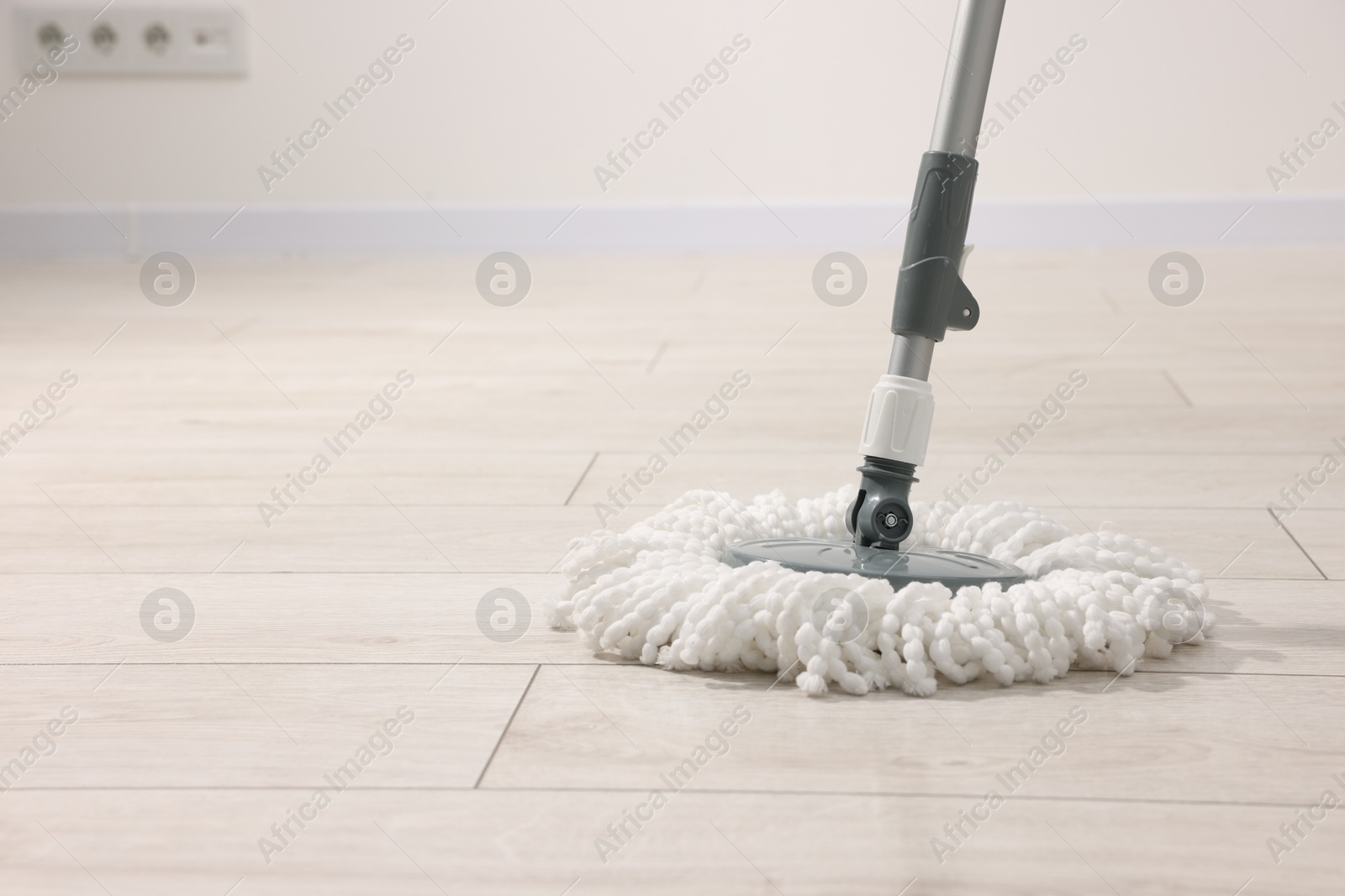 Photo of String mop on wooden floor indoors, space for text. Cleaning equipment