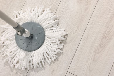 Photo of String mop on wooden floor indoors, above view. Space for text