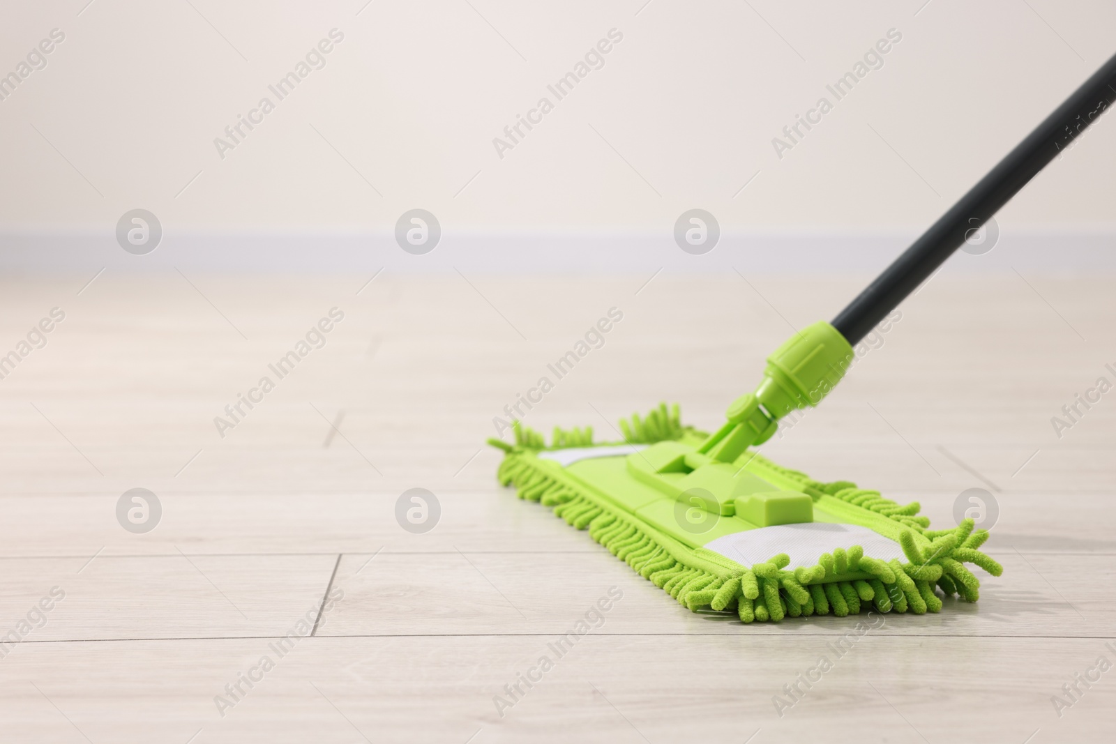 Photo of Microfiber mop on wooden floor indoors, space for text. Cleaning equipment