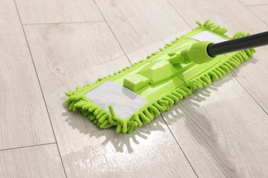 Photo of Microfiber mop on wooden floor, closeup. Cleaning equipment