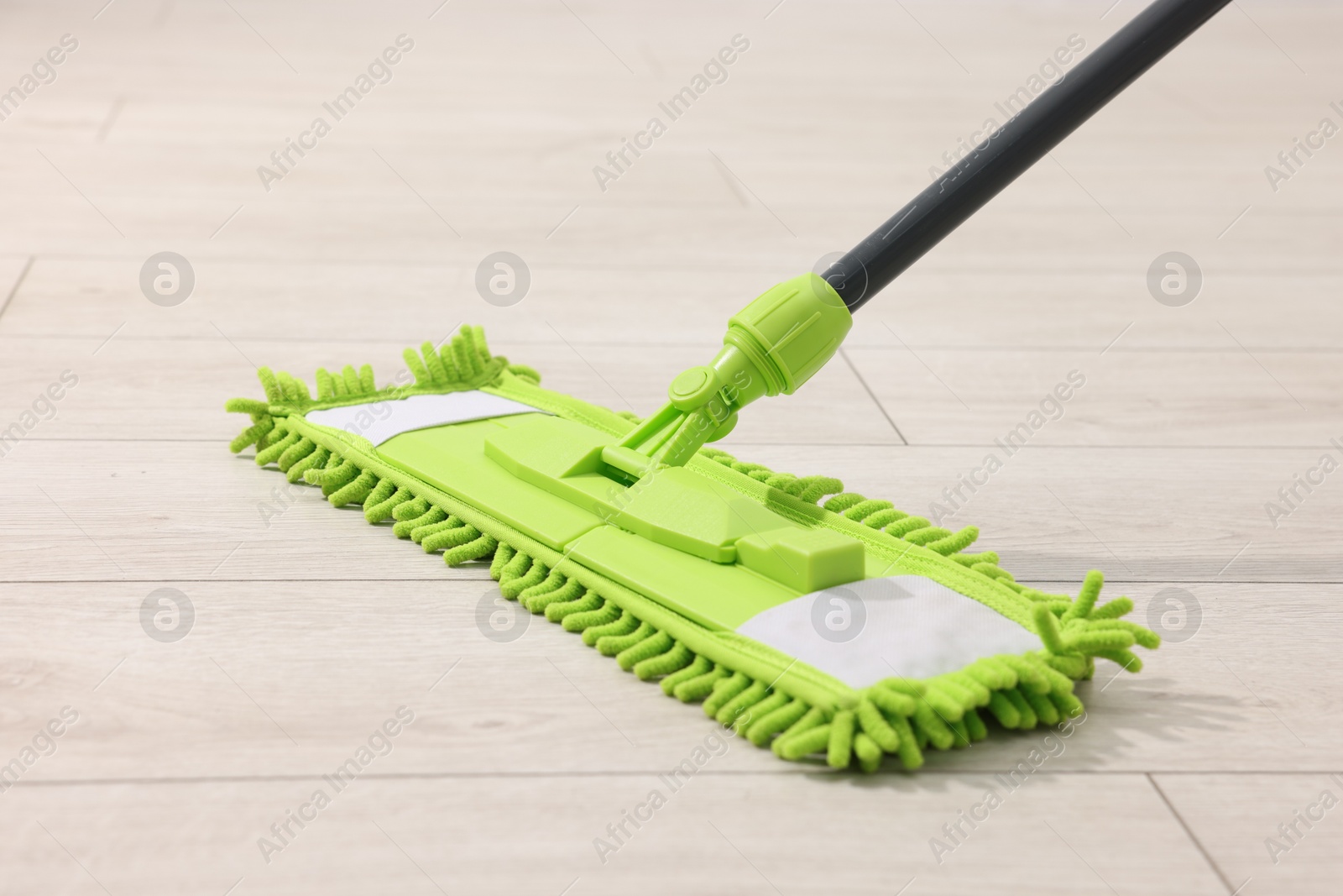 Photo of Microfiber mop on wooden floor. Cleaning equipment