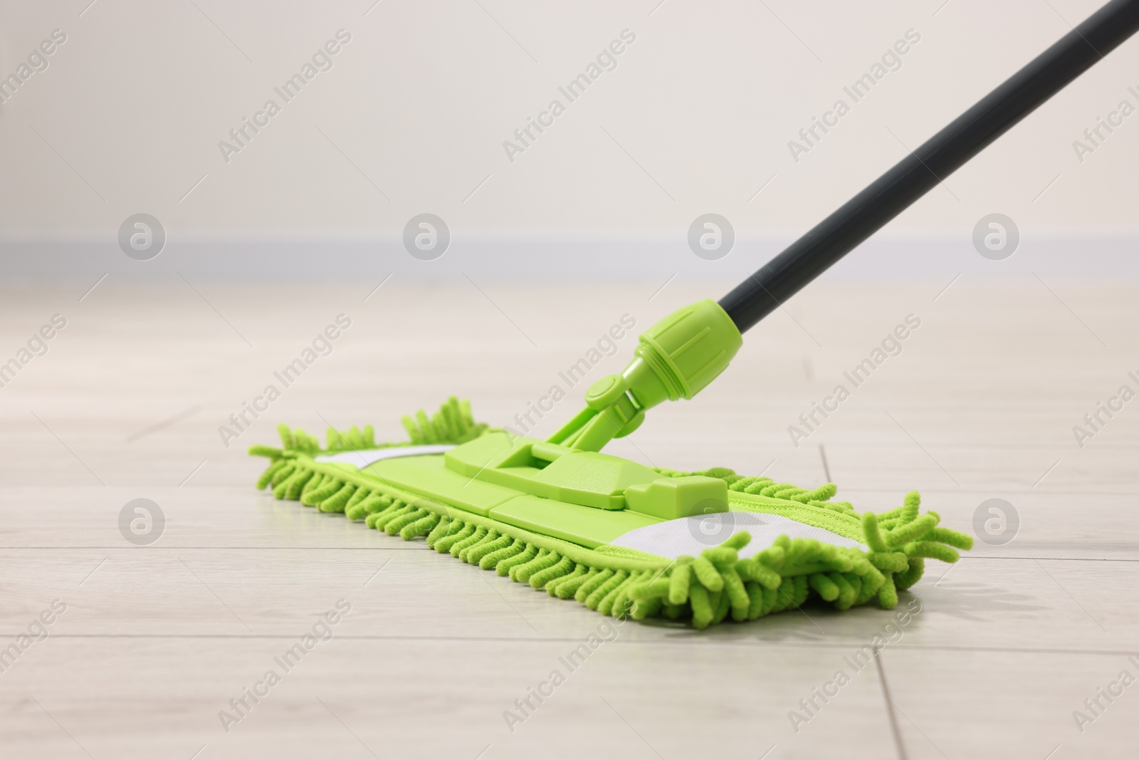 Photo of Microfiber mop on wooden floor indoors. Cleaning equipment