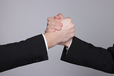 Photo of Businessmen competing on grey background, closeup view