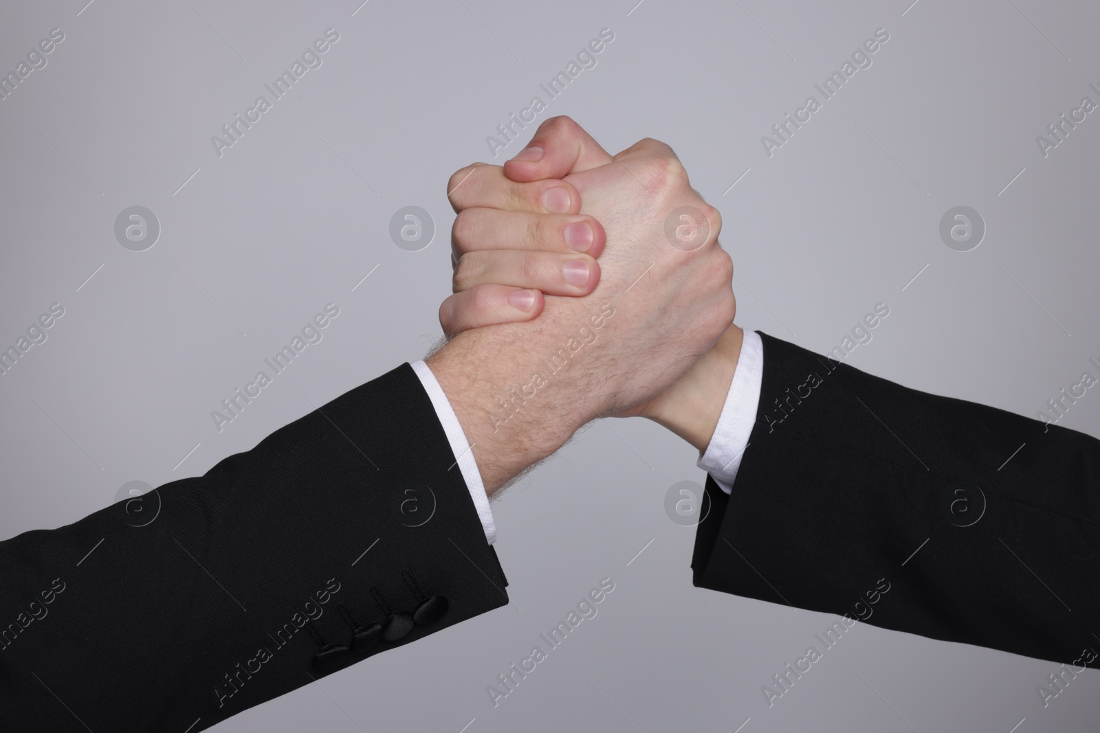 Photo of Businessmen competing on grey background, closeup view