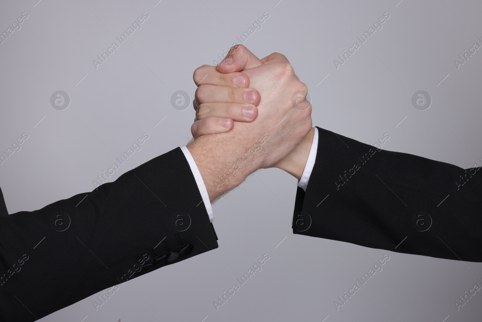 Photo of Businessmen competing on grey background, closeup view