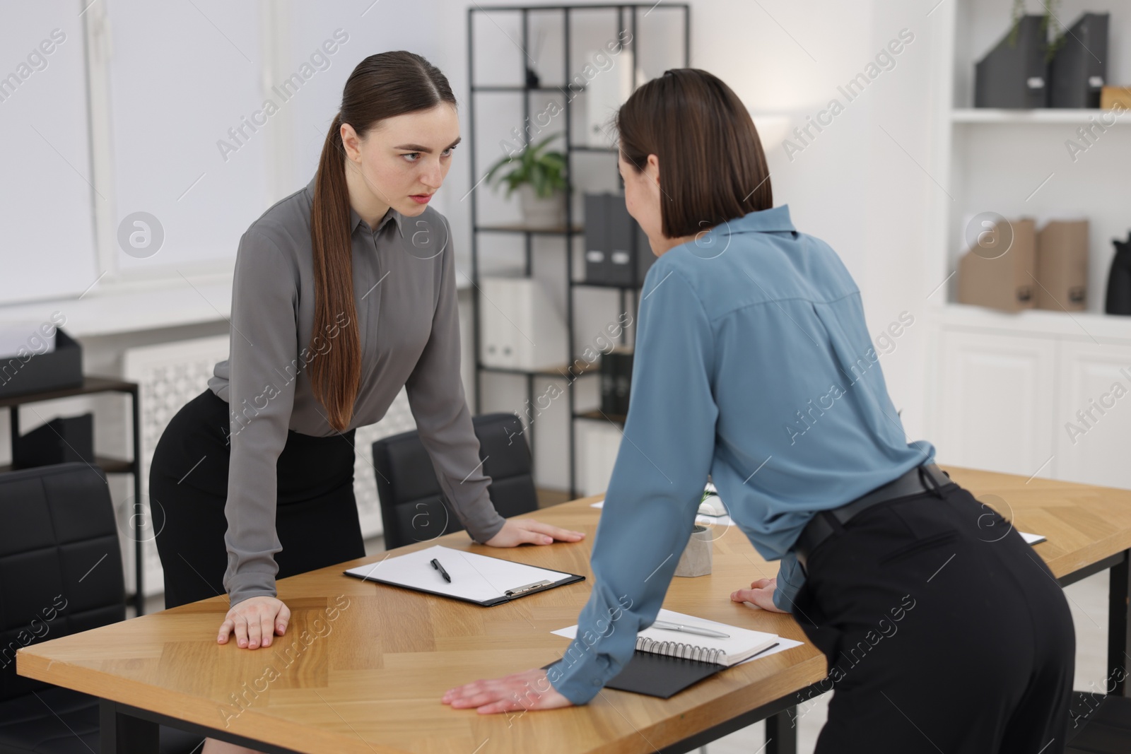 Photo of Competition concept. Businesswomen looking and examining each other at table in office