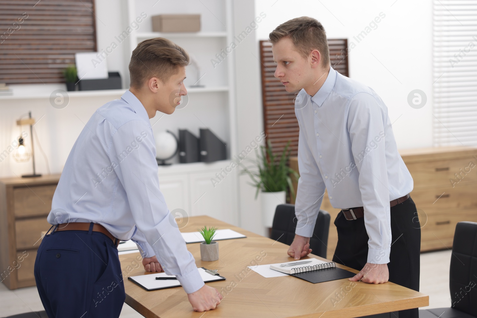 Photo of Competition concept. Businessmen looking and examining each other at table in office