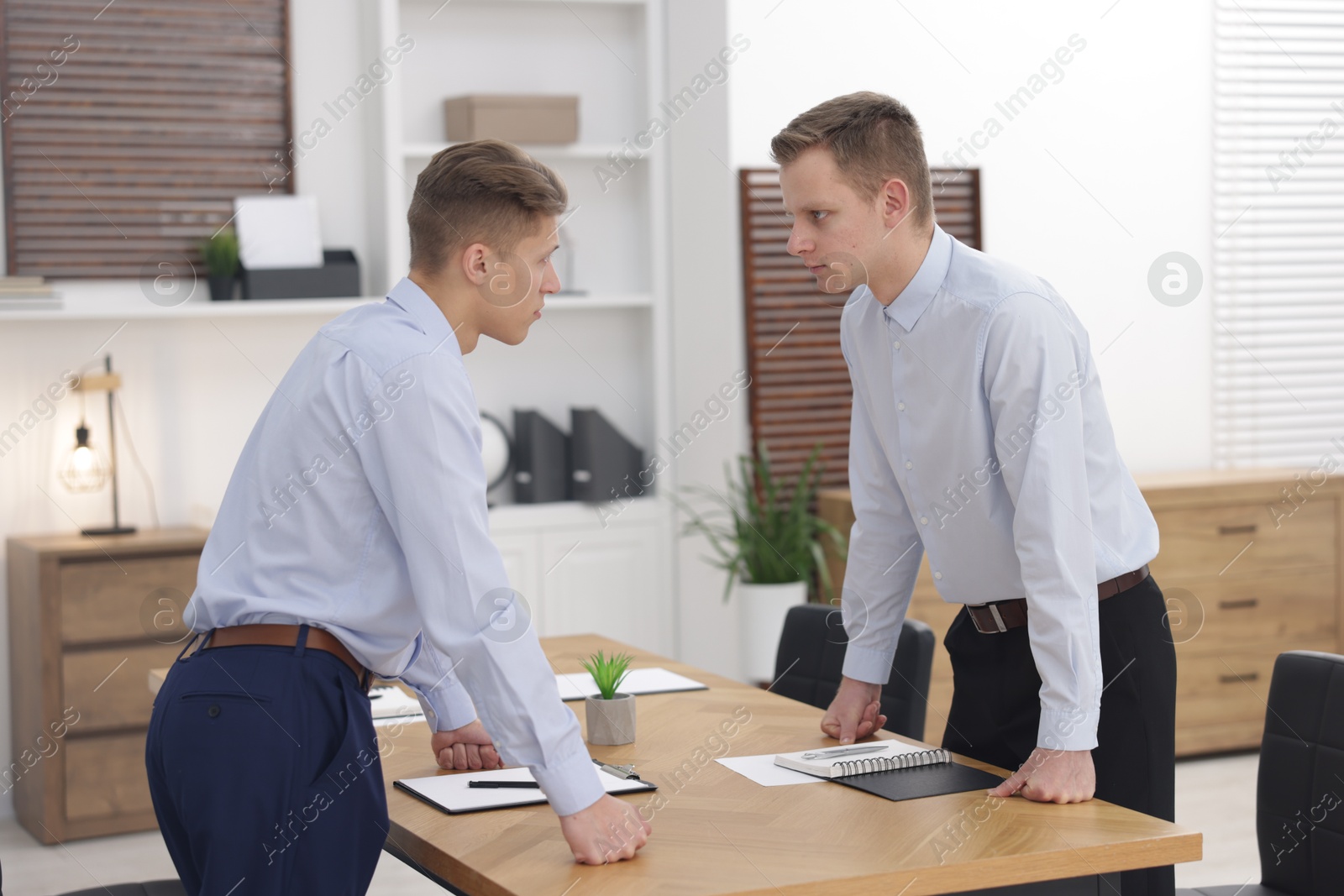 Photo of Competition concept. Businessmen looking and examining each other at table in office